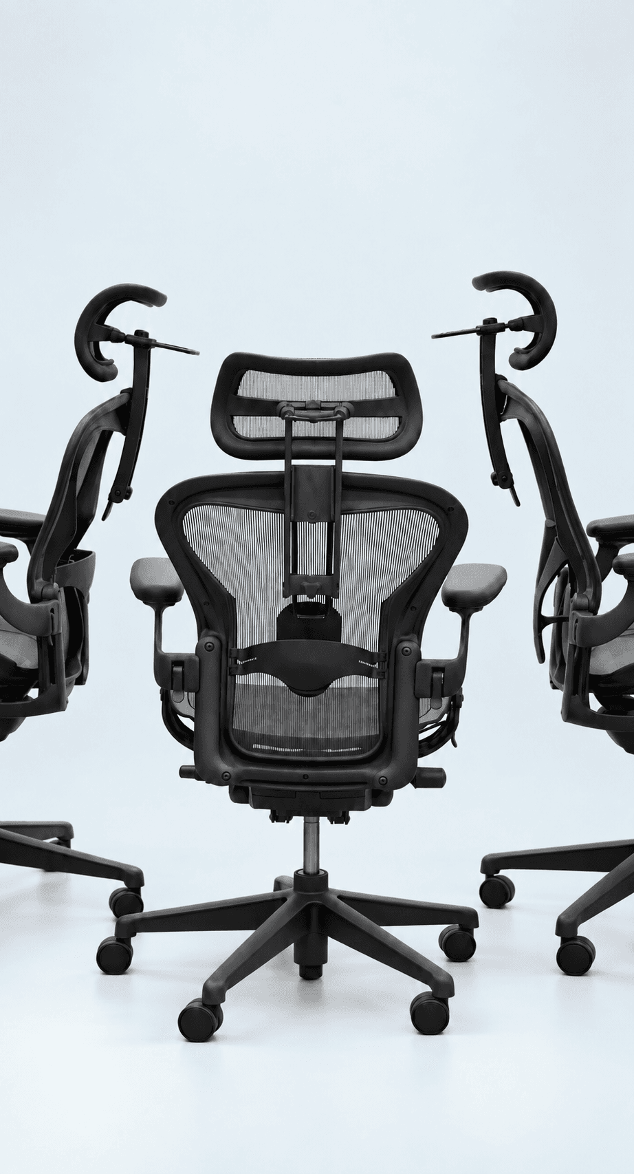 Black ergonomic chair viewed from the rear with a headrest and two chairs at its sides